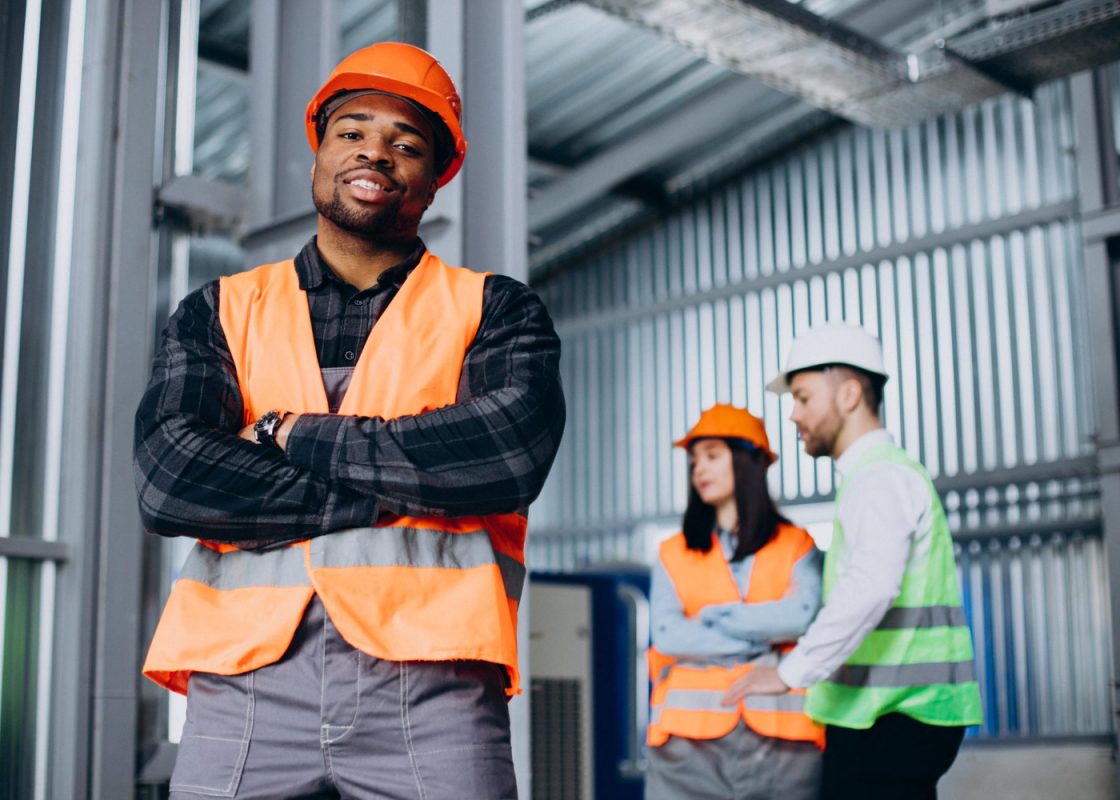 Three Factory Workers Safety Hats Discussing Manufacture Plan